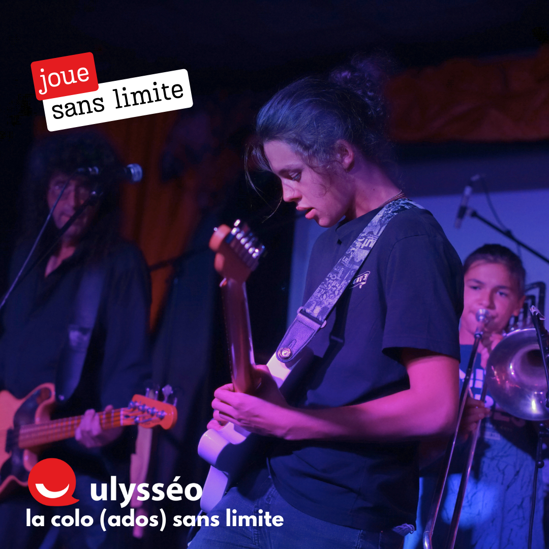 Ado jouant de la guitare sur scène avec son groupe